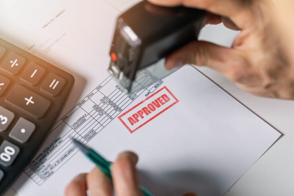 Legal looking document on a desk with a big, red stamp "Approved" to illustrate Signifyd's pre-authorization vs. post-authorization blog post.